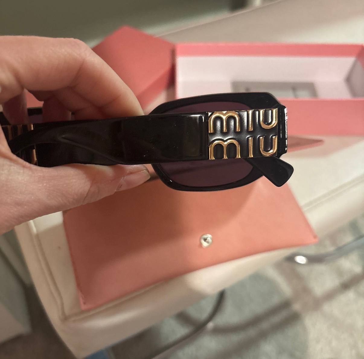 Lunettes de soleil Miu Miu noires logo doré